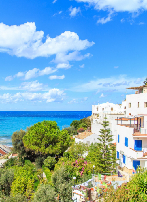 Vista costiera con case bianche e mare blu sotto un cielo sereno.