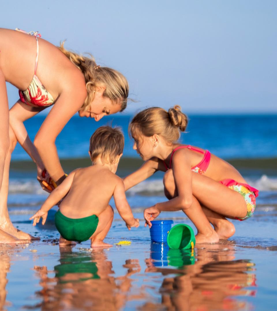 Family playing on the beach with bucket and sand.